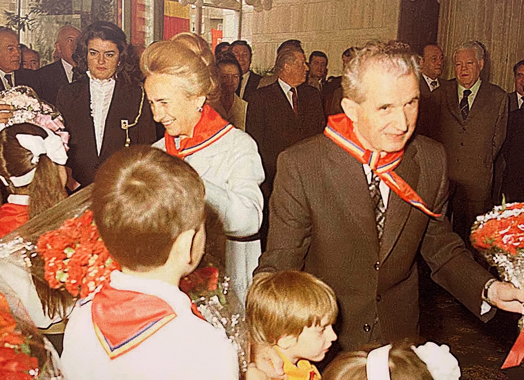 Nicolae and Elena Ceauşescu receiving bouquets of flowers from children who have been especially selected to adore the couple.
