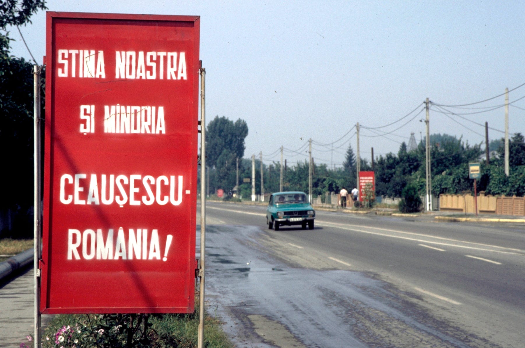 A road sign in the town of 30 Decembrie (30 December), south of Bucharest, when I visited in 1987.  The sign, typical of hundreds across Romania at the time, means “Our esteem and pride – Ceauşescu – Romania!”.  