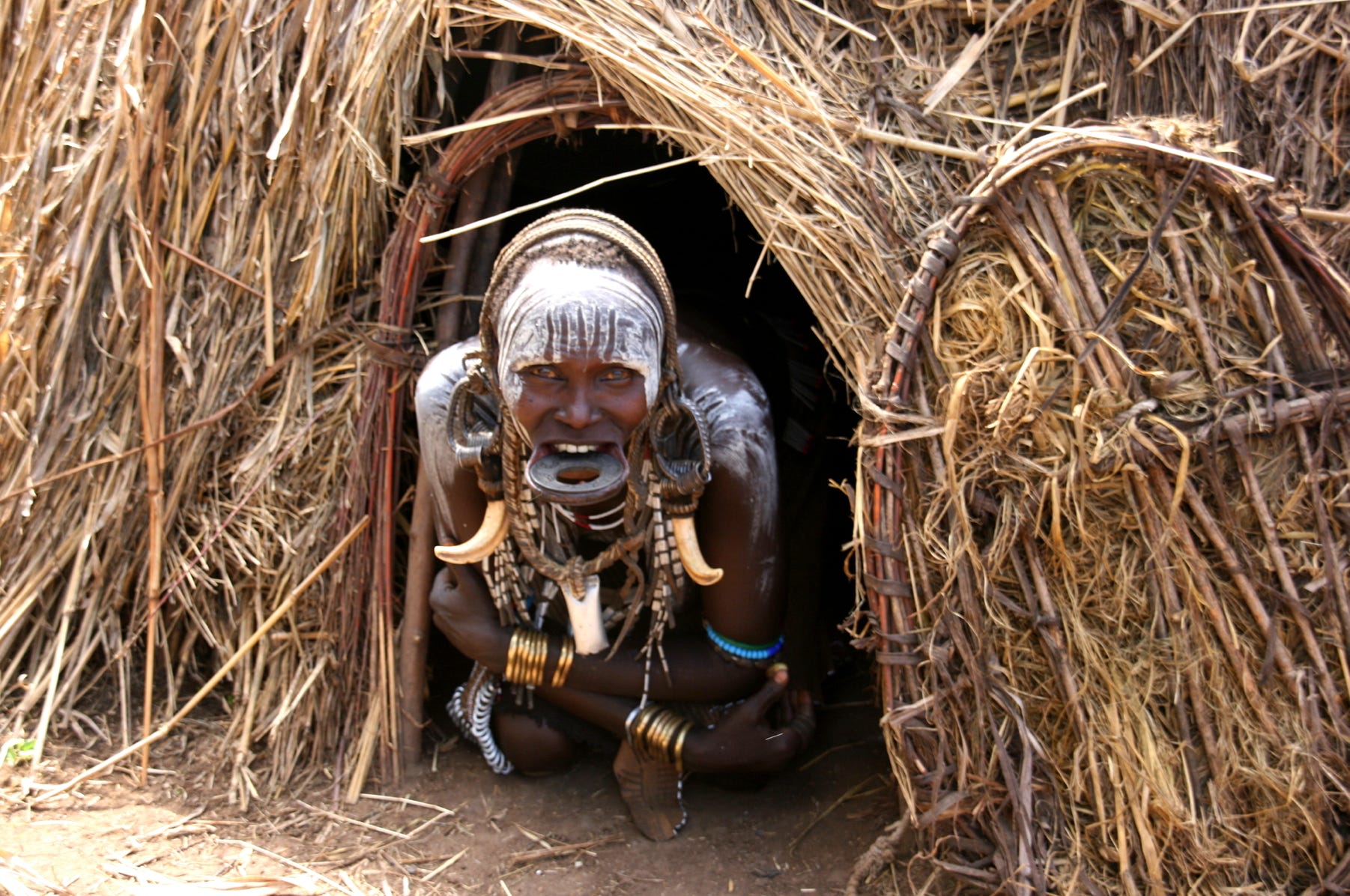 A resident in a Mursi settlement in the Omo Valley of Ethiopia looks out from the front of her dwelling.