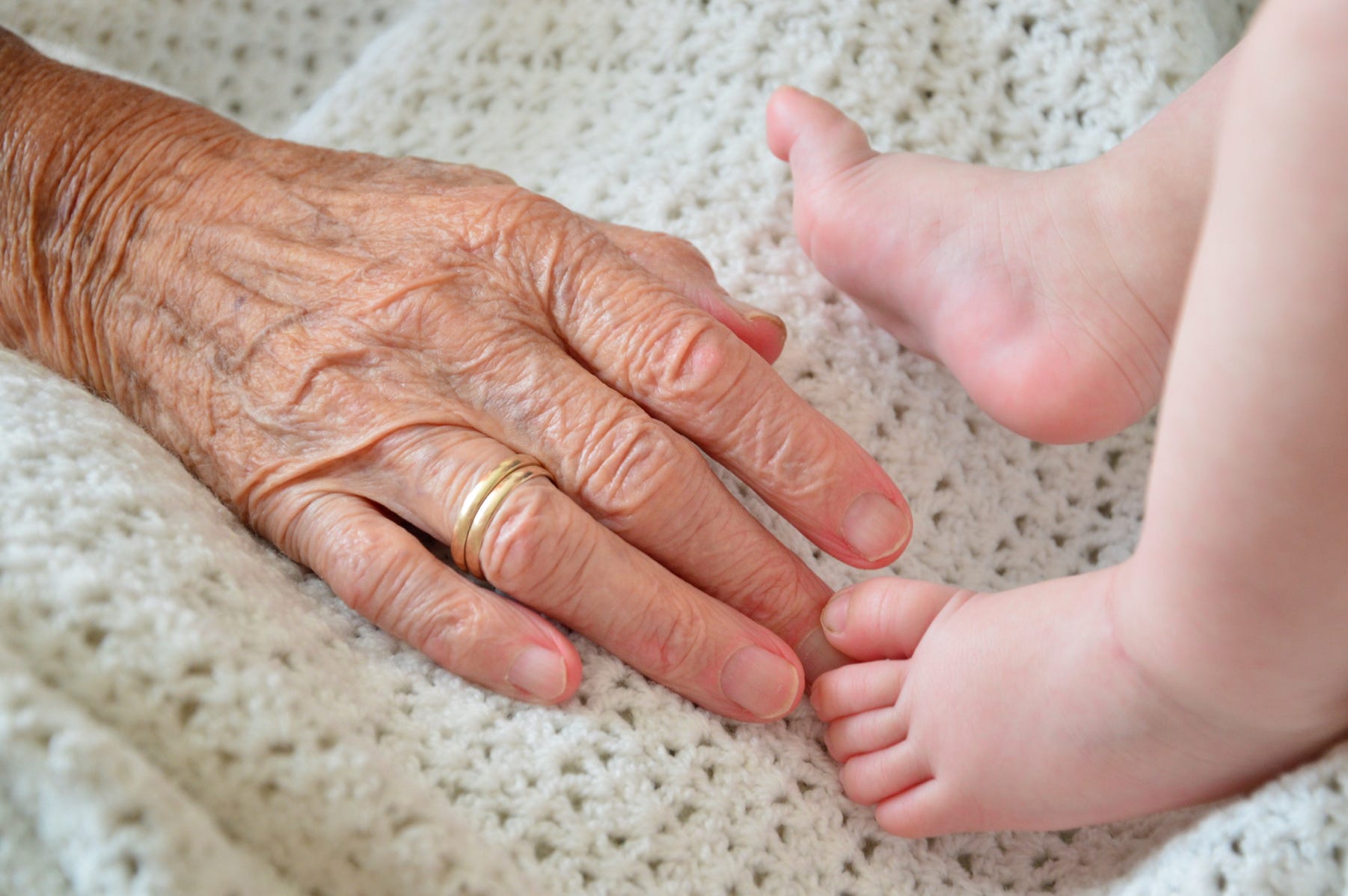 Elderly hand with baby's feet